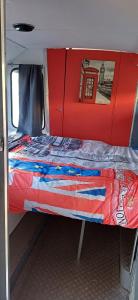 a bed in a room with a red door at insolite bus anglais le Buckinghambus in Saint-Philbert-sur-Risle