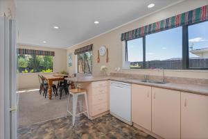 a kitchen with a sink and a dining room with a table at Family Friendly-Whitianga in Whitianga
