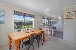 a dining room and kitchen with a wooden table and chairs at Family Friendly-Whitianga in Whitianga