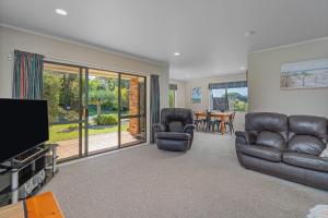 a living room with two leather chairs and a flat screen tv at Family Friendly-Whitianga in Whitianga