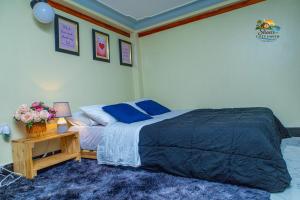 a bedroom with a bed with blue pillows and a table at Shan cozy haven in Jinja