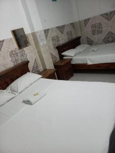 a bedroom with two beds and a tv on the wall at Hotel La Palma Girardot in Girardot