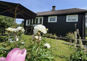 a garden with white flowers and an umbrella at Rustic Haven Bed and Breakfast -Entire Private Apartment 2km from Klarälvsbanan and Swimming area in Munkfors