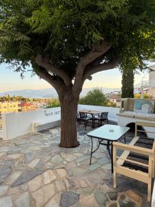 a tree on a patio with tables and chairs at Agia Anna Horizon in Kranidi