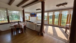 a kitchen with a table and chairs and windows at Pensiunea Teodora in Dorna Arini
