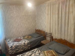 a bedroom with two beds and a window with curtains at noras guesthauze 2026 in Zhabeshi
