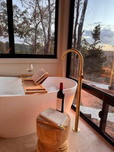 Eine Badewanne mit einer Flasche Wein neben einem Fenster in der Unterkunft Zenith Tiny Home in Montacute + 20 Fotos