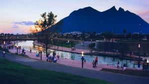 a group of people walking by a river with a bridge at La Pastora in Monterrey