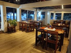 a restaurant with wooden tables and chairs and windows at Cherai Beach View Heritage in Cherai Beach