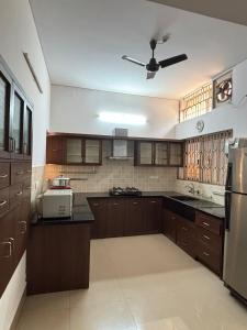 a kitchen with brown cabinets and a ceiling fan at 3bhk villa in Lalbagh in Mangalore