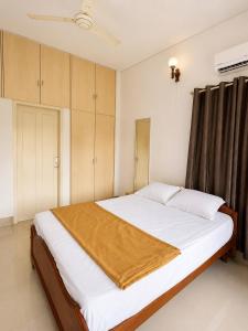 a bedroom with a bed with white sheets and wooden cabinets at 3bhk villa in Lalbagh in Mangalore