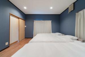 two beds in a bedroom with blue walls at Shima Yadori Nagomi in Oshima +47 photos
