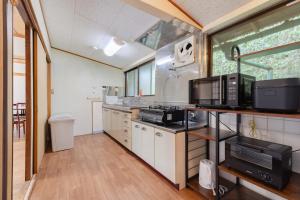 a large kitchen with a stove and a microwave at Shima Yadori Nagomi in Oshima