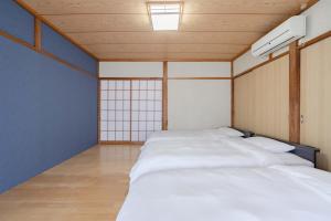 a room with four white beds in it at Shima Yadori Nagomi in Oshima