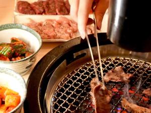 a person is cooking food in a grill at 別館JOUNi in Niijimamura +15 photos