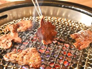 a grill with meat and bacon being fried on it at 別館JOUNi in Niijimamura