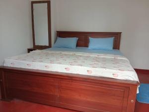 a large wooden bed with a wooden frame and blue pillows at NIVRA Homestay in Kumbalwela