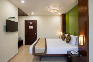 a bedroom with a bed and a flat screen tv at TSG Emerald View Hotel and SPA in Port Blair +50 photos