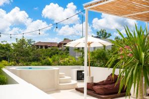 an outdoor patio with a pool and an umbrella at Ôkeanos Boutique Hotel - Uluwatu Ungasan in Uluwatu