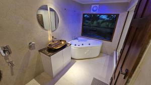 a bathroom with a sink and a tub and a mirror at Navora Houseboats in Alleppey