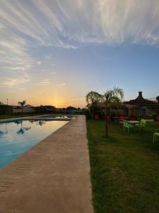 a pathway next to a pool with the sunset in the background at La ferme labyed in Fez