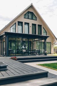 a large house with glass windows and a wooden deck at Brīvdienu māja Daugavas rezidence in Ķegums