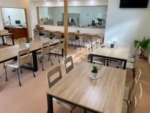 a restaurant with wooden tables and chairs and a cafeteria at あらとんとんの宿 in Setouchi