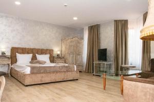 a bedroom with a bed and a couch and a television at Хотел Терес in Kazanlŭk