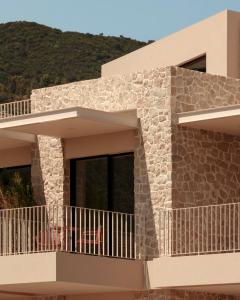 a house with a balcony with a mountain in the background at Petra Mare Villas in Psathopyrgos