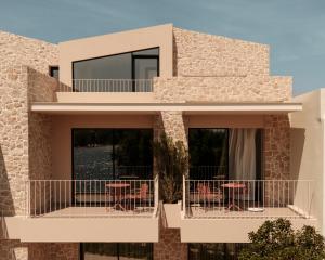 a house with a balcony with tables and chairs at Petra Mare Villas in Psathopyrgos +106 photos