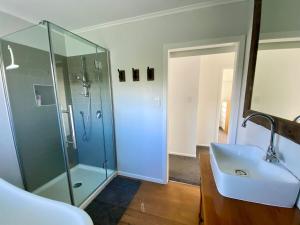 a bathroom with a glass shower and a sink at Cable Bay Moana View House in Cable Bay +39 photos