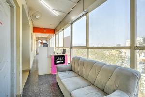 a couch in the middle of a room with windows at Collection O Kadugodi Tree Park Metro Station Bengaluru Formerly Royal Rooms in Bangalore