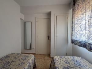 two beds in a room with a mirror and a door at NEW UDYNO in Piles +1 photo