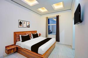 a bedroom with a bed and a tv and a window at Townhouse Vikas Nagar Lucknow Formerly Wave BLU in Lucknow