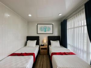 two beds in a small room with a window at Bhuana Agung Villa and Restaurant in Jatiluwih
