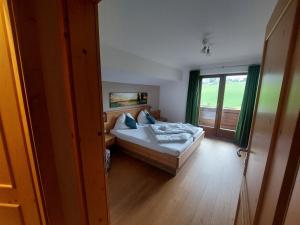 a bedroom with a bed and a large window at Alpen Appartements in Embach