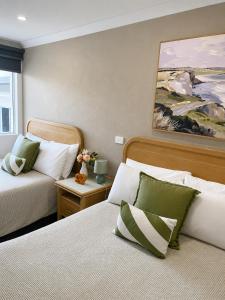 a bedroom with two beds and a painting on the wall at Chelsea Motor Inn in Coffs Harbour