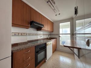 a kitchen with wooden cabinets and a sink and a stove at Voramar VI in Piles