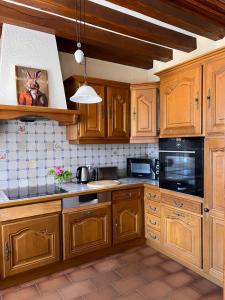 a kitchen with wooden cabinets and black appliances at Le Clos Colette in Neuvy