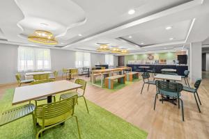 a waiting room with tables and chairs and a cafeteria at Spark by Hilton Milford Boston in Milford