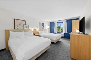 a hotel room with two beds and a flat screen tv at Spark by Hilton Milford Boston in Milford +83 photos