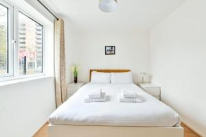 a white bedroom with a white bed and a window at Paprika Nest in Hendon