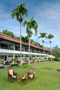 a resort with two chairs and a table and palm trees at Grand Whiz Hotel Trawas Mojokerto in Trawas