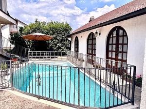 a swimming pool with an umbrella next to a house at Royal Sun Villa in Sarajevo