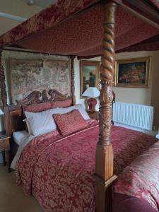 a bedroom with a canopy bed with a red bedspread at Beggar's Knap in Dorchester