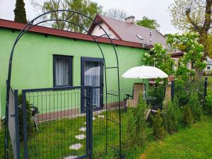 a green house with a fence and an umbrella at Domek dla dwojga w Stegnie in Stegna
