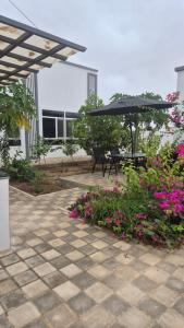 a patio with a table and an umbrella and flowers at بيت الريف in Salalah