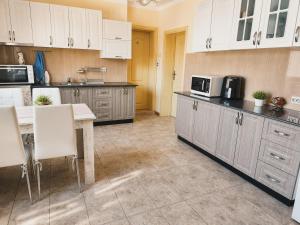 a kitchen with white cabinets and a table with chairs at ApartmentDanny in Hisarya