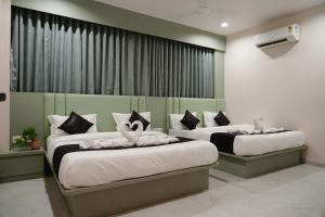 a bedroom with two beds with white sheets at Hotel The Avanta- Naroda in Naroda