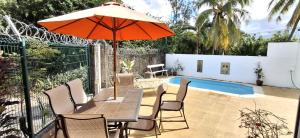 a table with an umbrella and chairs next to a pool at Bay Rose in Pointe d'Esny